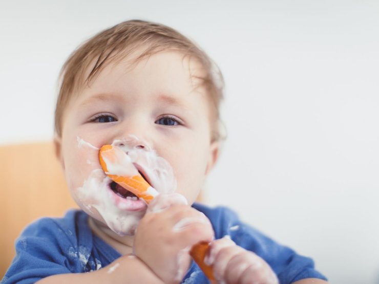 bambino che mangia da solo con cucchiaio 