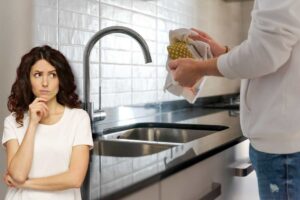 Lavare i piatti, in primo piano donna pensierosa