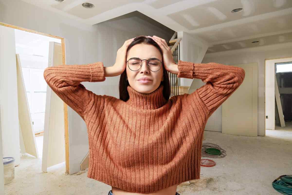 Donna con mani tra i capelli e casa sporca