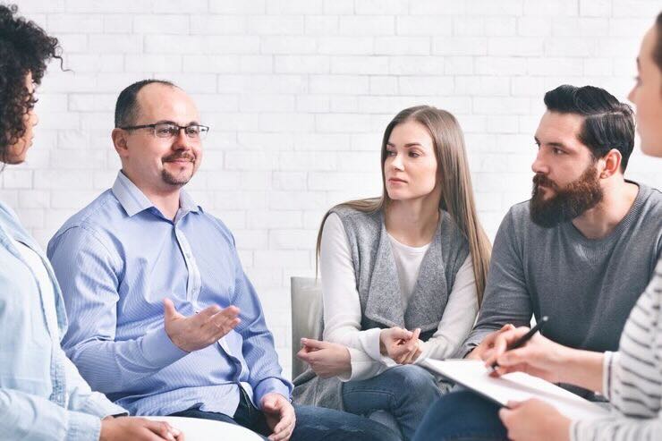 Persone riunite in cerchio ascoltano uomo che parla 