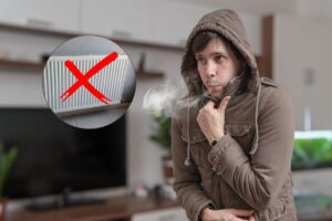 uomo che sente freddo in casa e termosifone con una x sopra