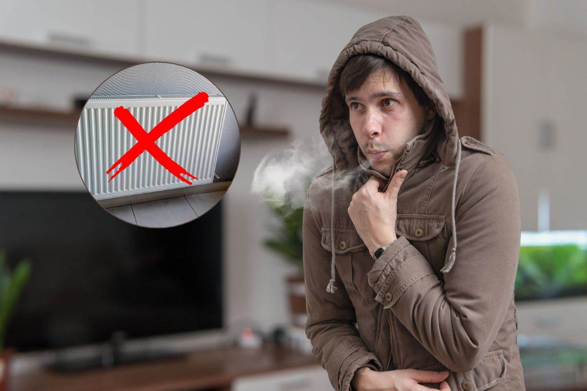 uomo che sente freddo in casa e termosifone con una x sopra